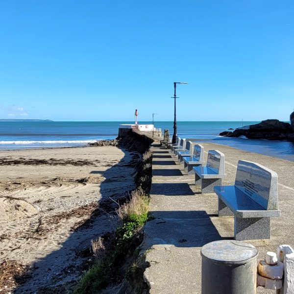 Stone benches of a pier surrounded by sandy beach and sea